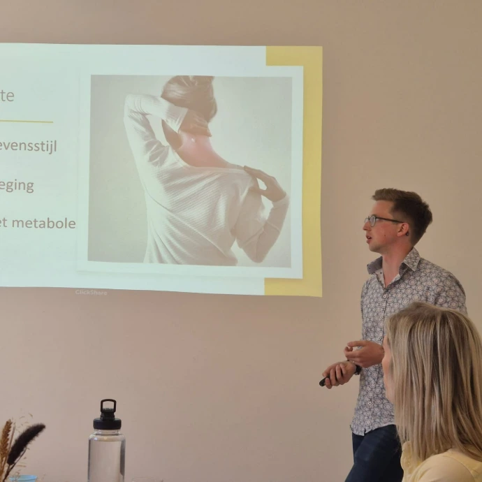 Een spreker geeft een presentatie met een geprojecteerde afbeelding tijdens een gezondheidssessie.